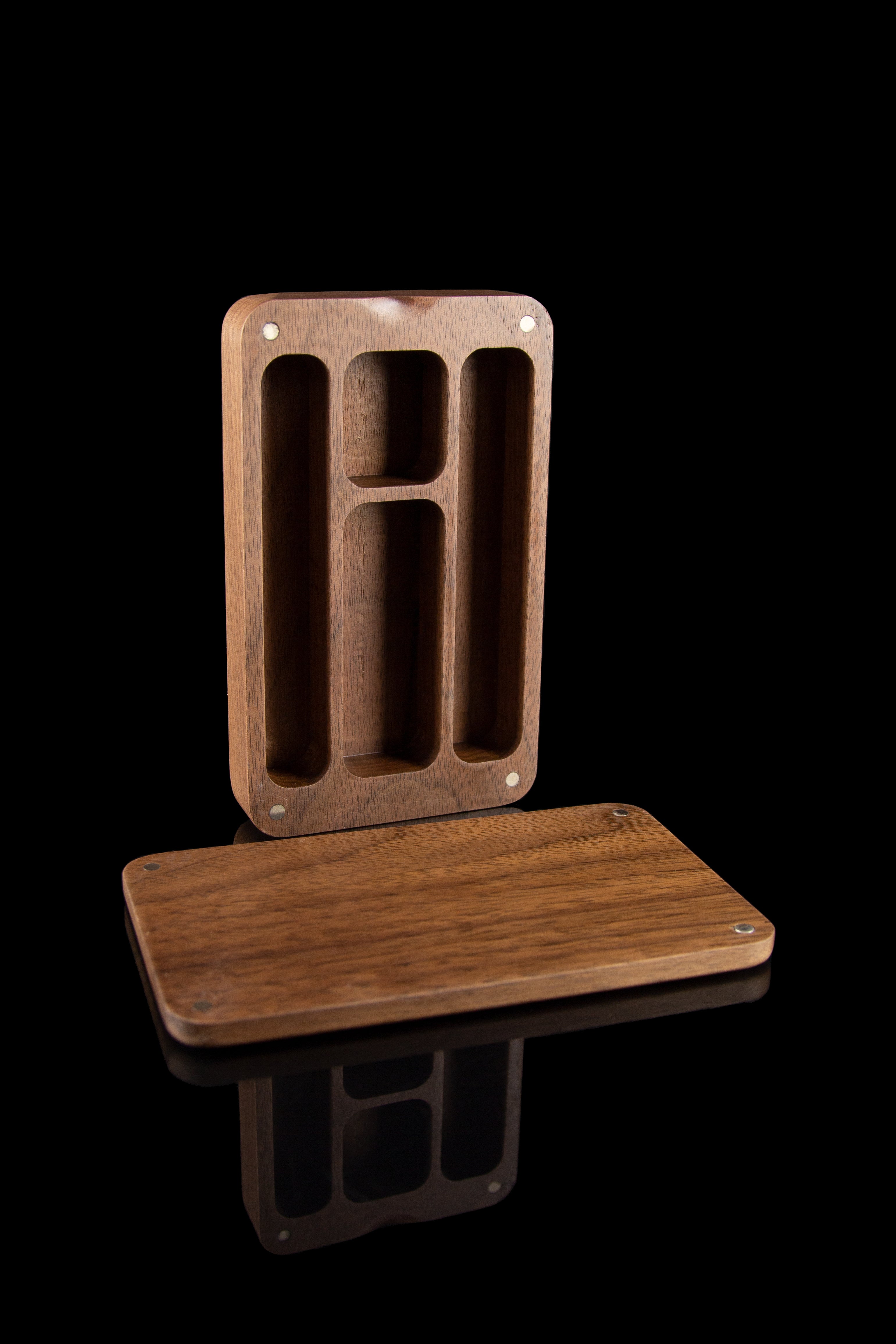 Wooden cannabis smoking accessory organizer with slots for tools and a small shelf, isolated on a black background.