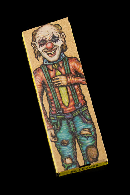 A rectangular, patterned rolling paper booklet featuring a darkly illustrated, menacing clown in overalls.