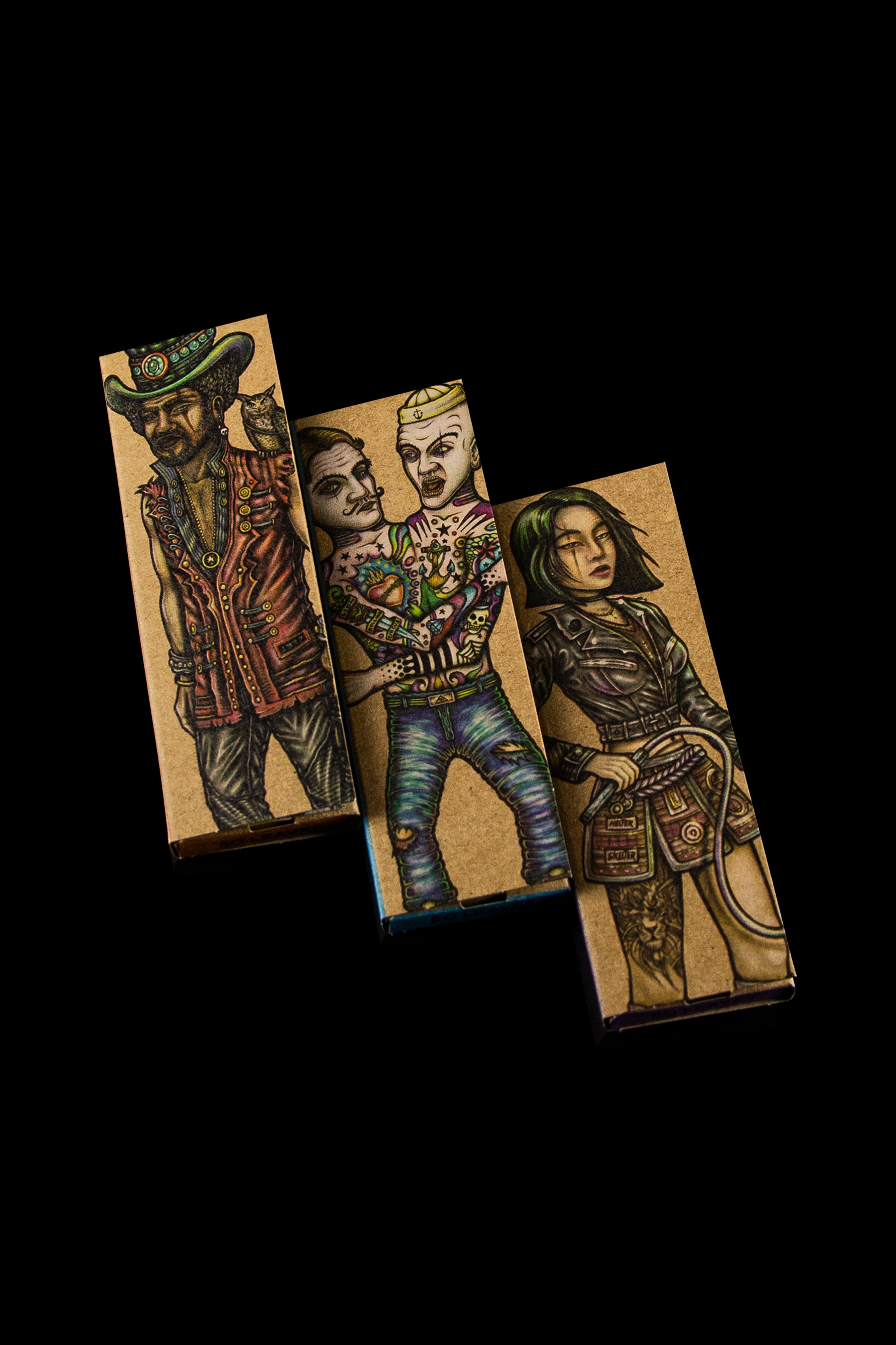 Three rectangular cannabis wrap boxes with illustrated character designs in a gothic, edgy style. 