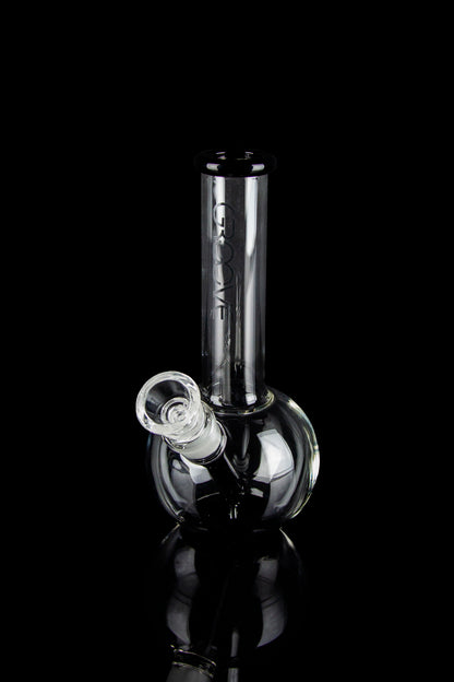 Clear glass bubbler water pipe with reflective surface, isolated on black.