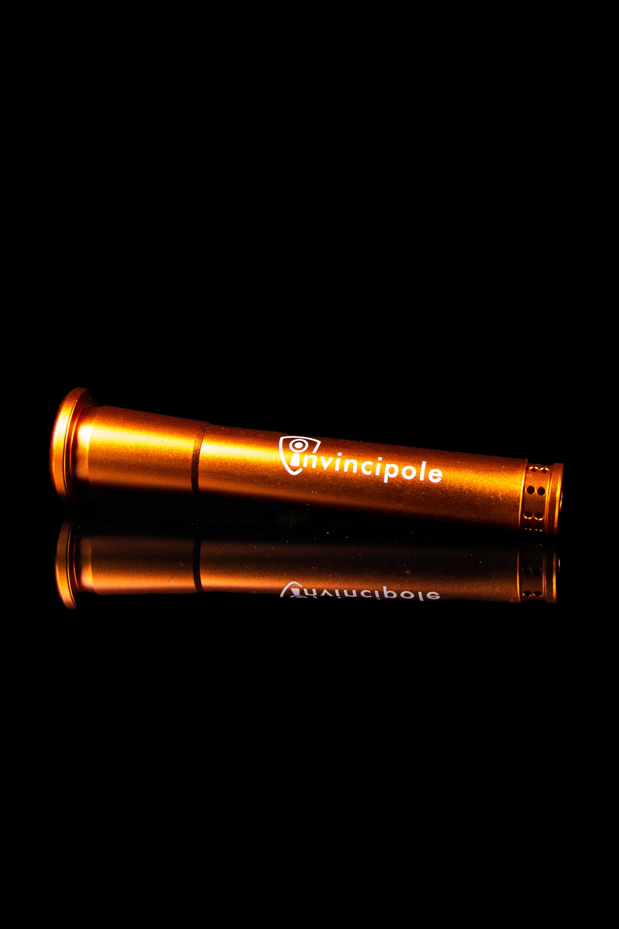 Orange Invincipole vaporizer pen reflecting on a dark surface.