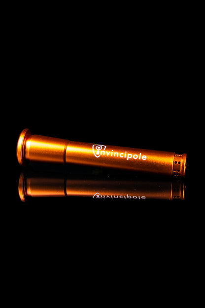 Orange Invincipole vaporizer pen reflecting on a dark surface.