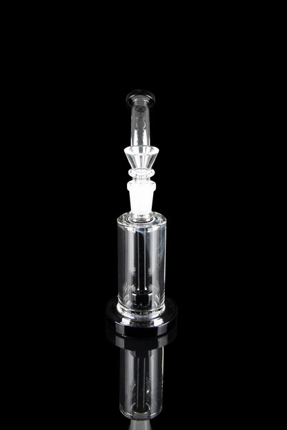 Clear glass dab rig with intricate percolator, reflecting on a black surface.