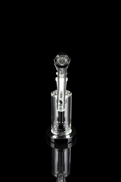 Clear glass water pipe (rig) with intricate design, reflecting on a black surface.