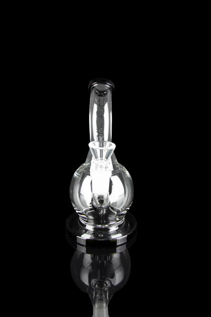 Clear glass dab rig with illuminated internal chamber, isolated on black.