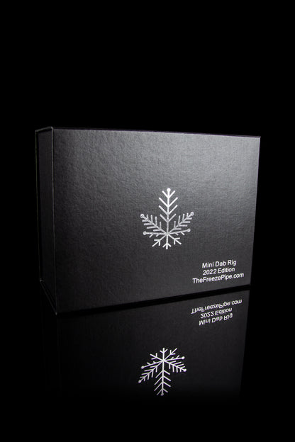 Black box for a cannabis mini dab rig, featuring a snowflake design and website address.