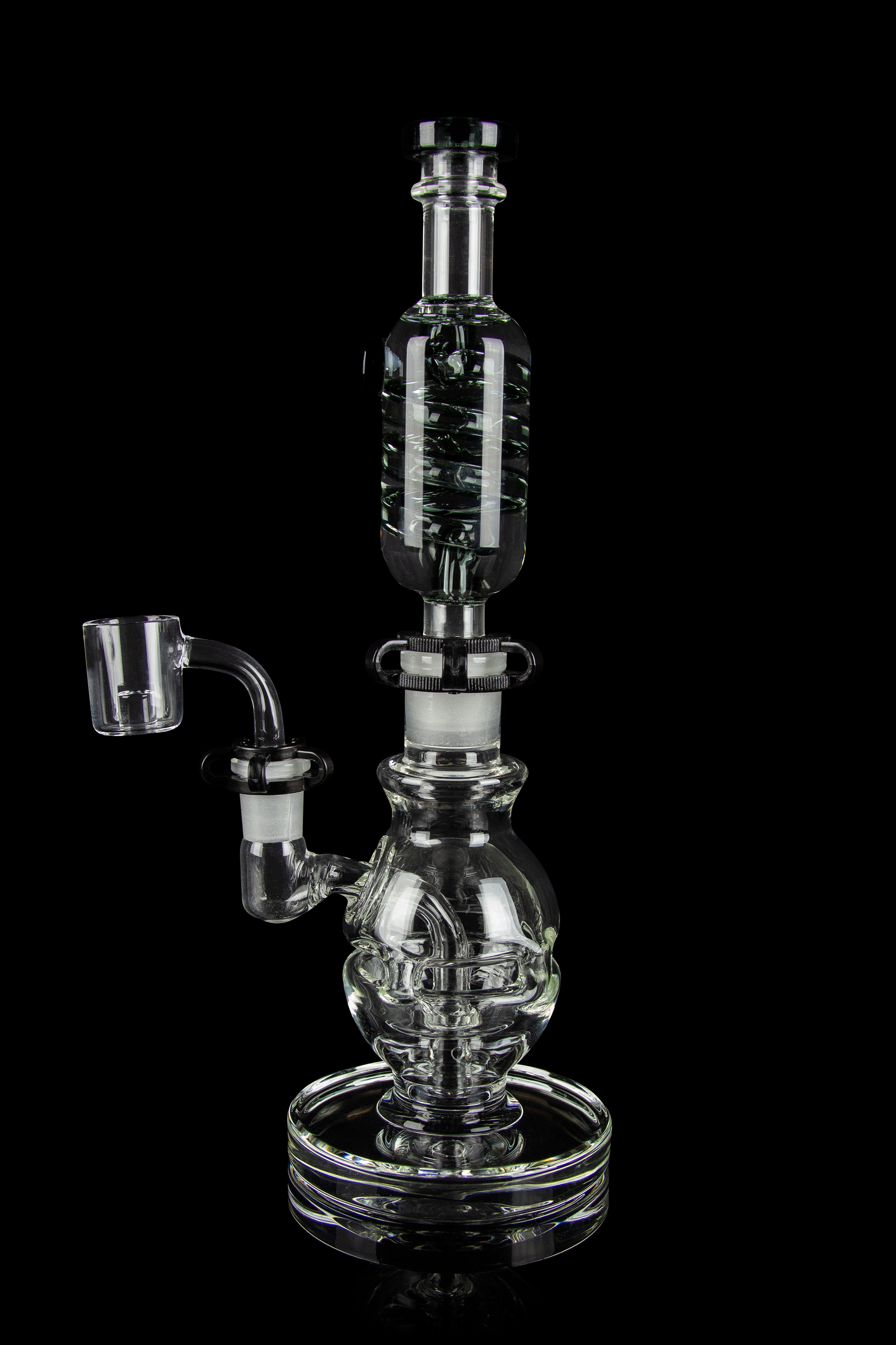 Clear glass dab rig with intricate bubbler design and quartz nail, isolated on black.