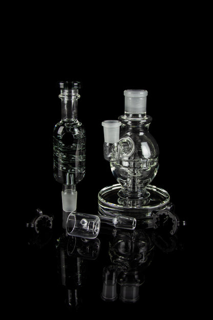 Clear glass dab rigs and accessories displayed on a reflective black surface.