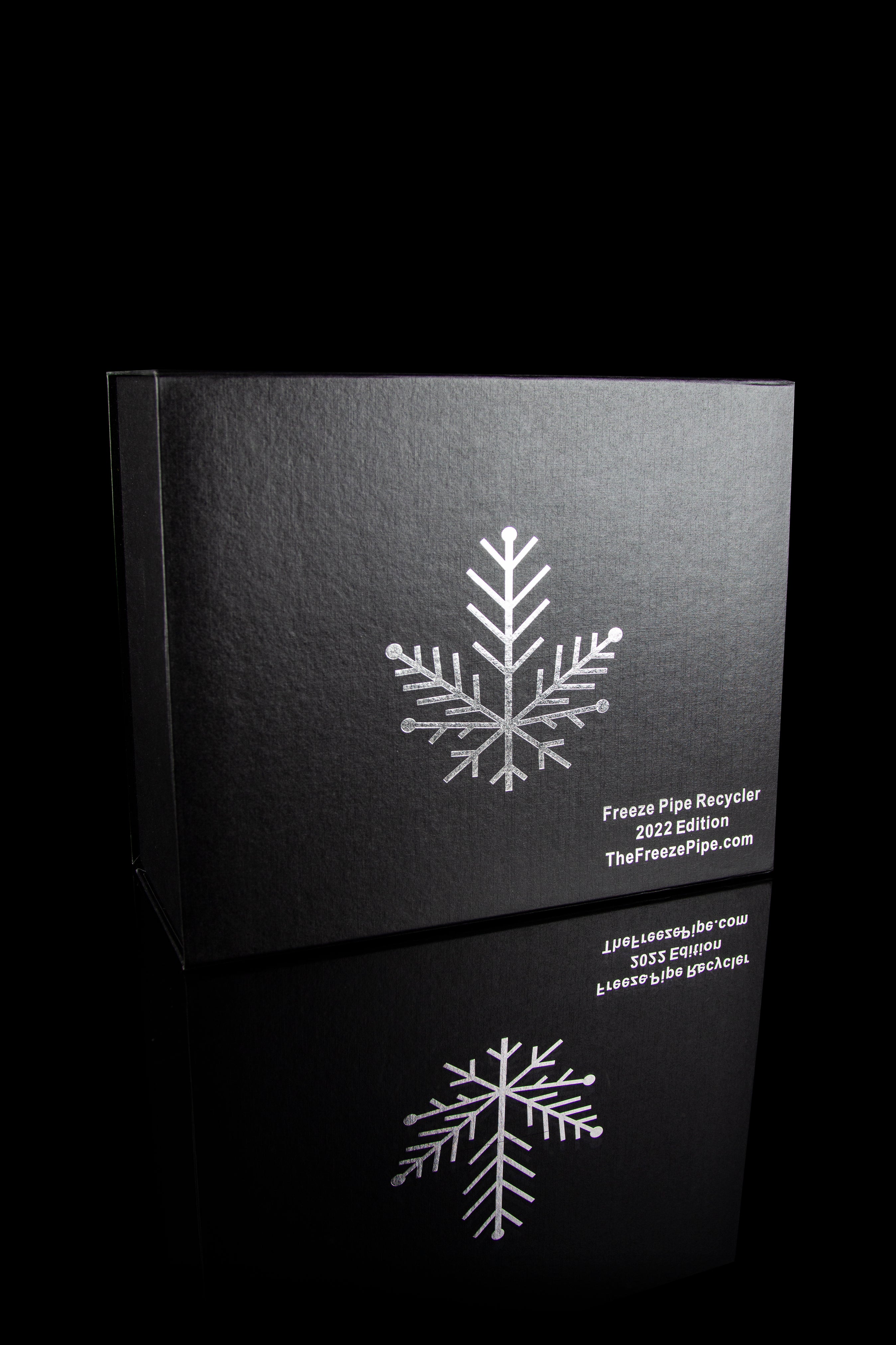Black box with silver snowflake design and text advertising "Freeze Pipe Recycler" and website "TheFreezePipe.com".