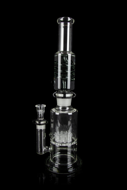 Clear glass water pipe (rig) with intricate percolator design, isolated on a black background.