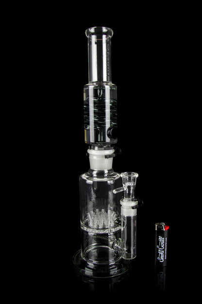 Clear glass water pipe (bong) with intricate percolator design, studio shot on black background.