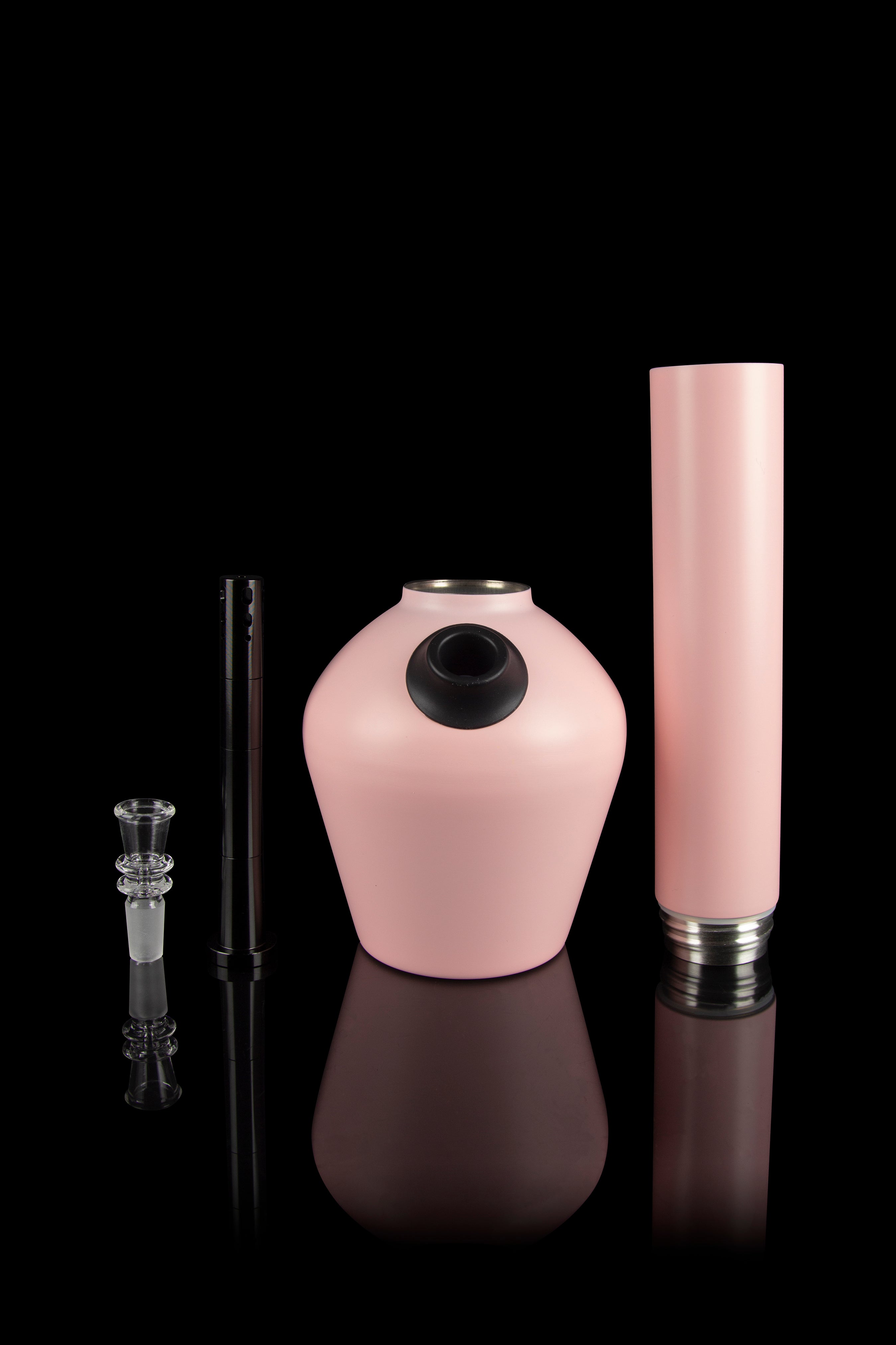 Pink glass water pipe, downstem, and cylindrical attachment displayed on a reflective surface.