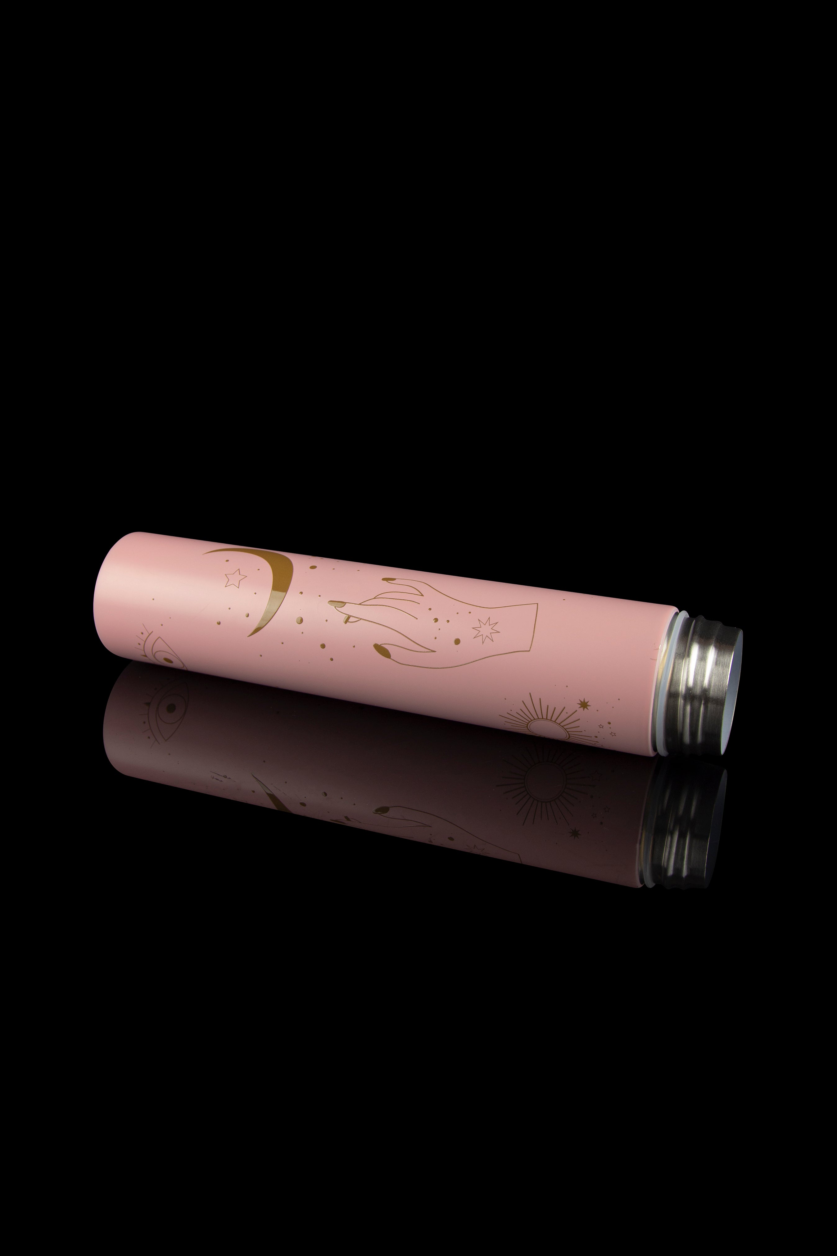 Pink cannabis container with celestial gold illustrations reflecting on a black surface.