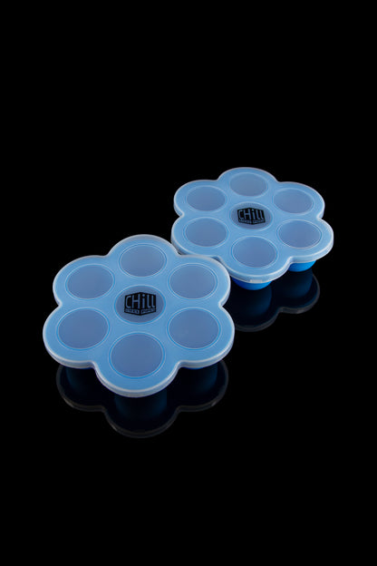 A high-angle view of the two Chill Steel Pipes Ice Cube Trays, showcasing their silicone construction and geometric design on a reflective surface.