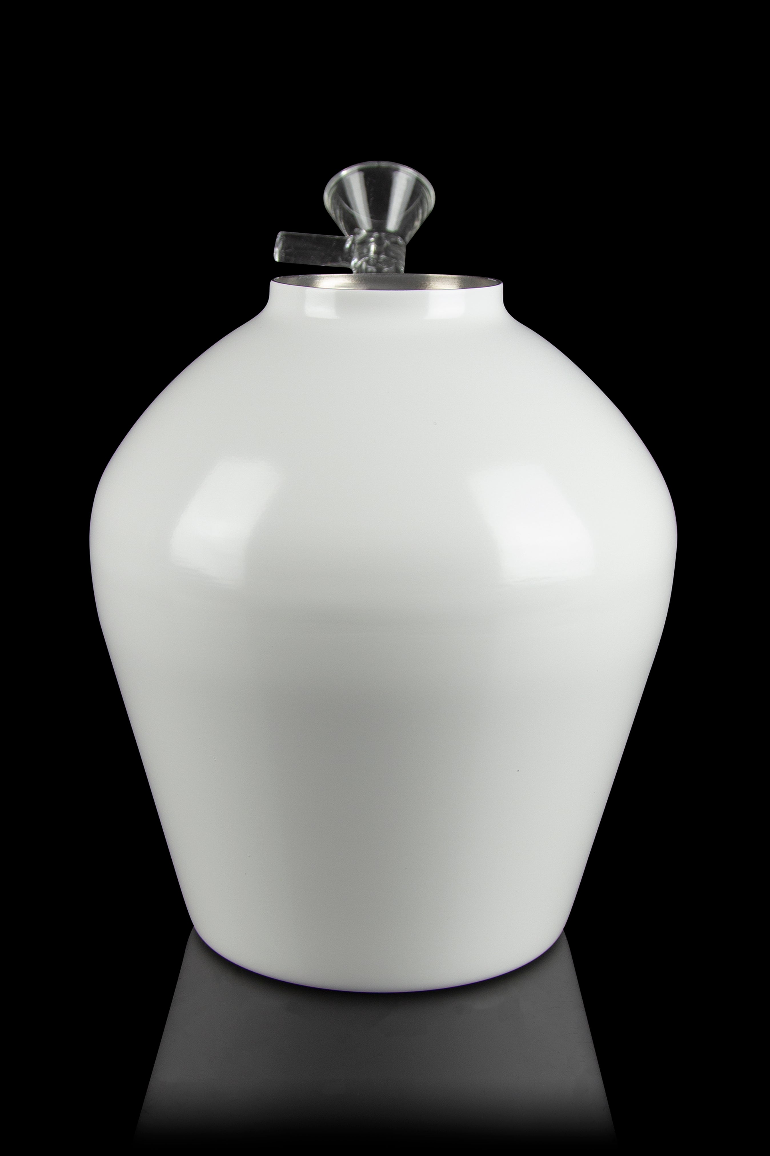 White glass solvent wash still with stainless steel valve and tubing, studio shot.
