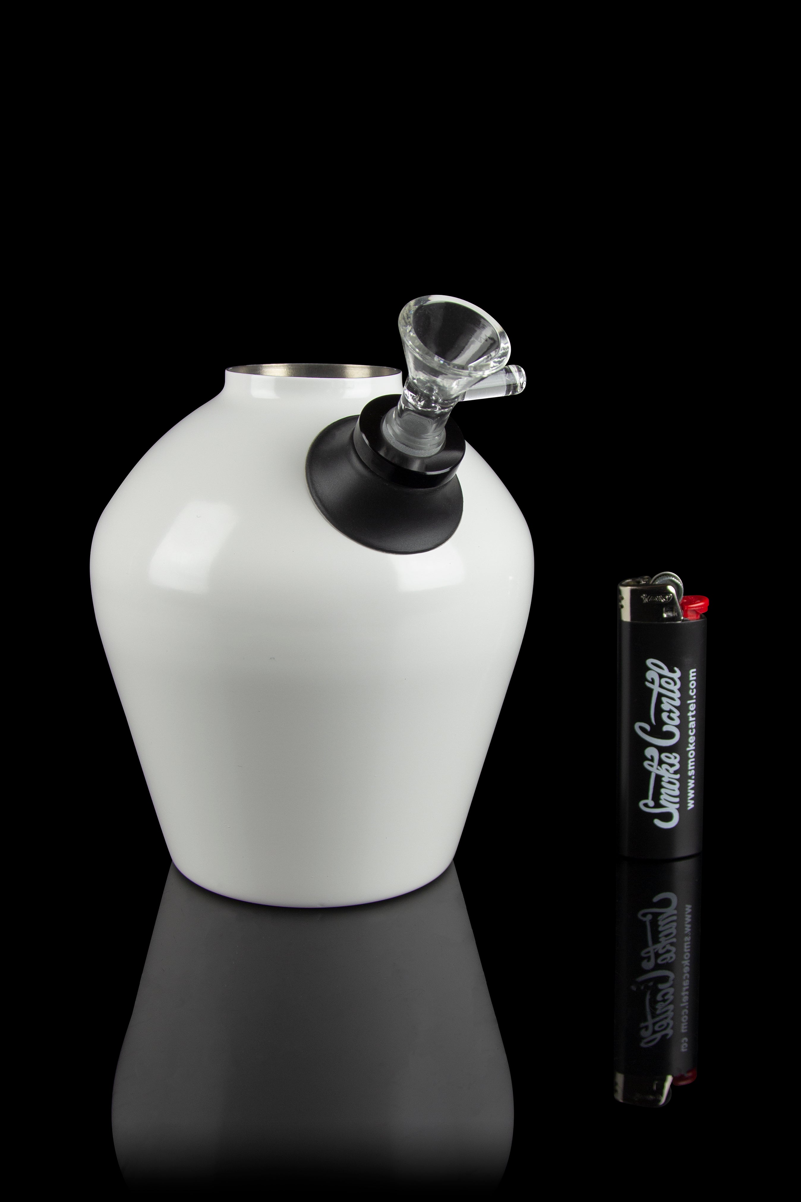 White glass water pipe with a glass bowl and lighter on a reflective black surface.