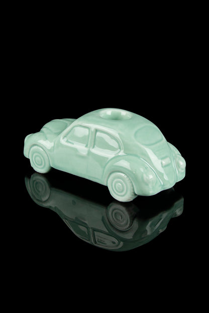 Mint green Volkswagen-shaped ceramic piece with a glossy finish, reflecting on a black surface.
