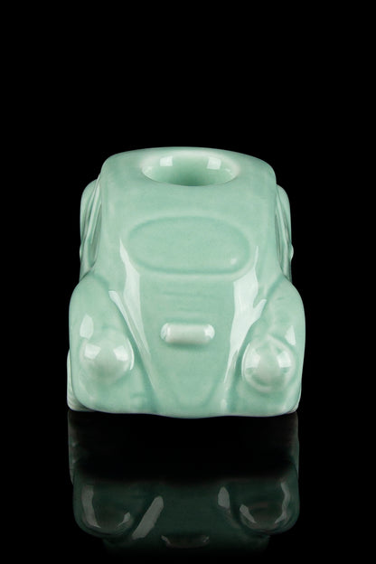 Mint green glass cannabis water pipe shaped like a classic Volkswagen Beetle, displayed on a reflective surface.