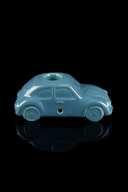 Teal glass pipe shaped like a vintage car with a reflective black surface.