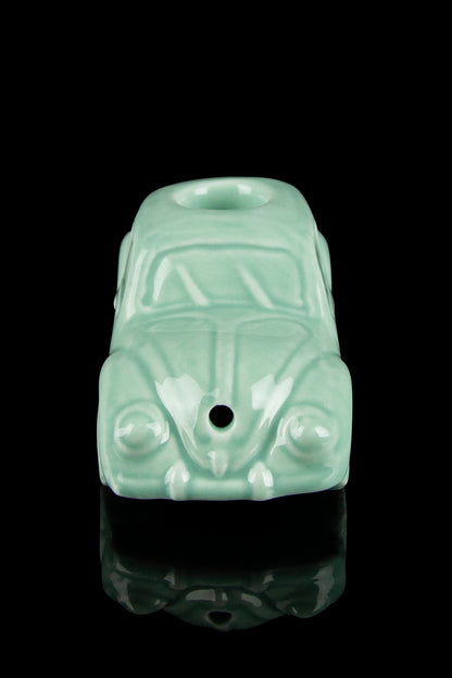 Mint green Volkswagen Beetle-shaped glass pipe with a glossy finish, reflecting on a black surface.