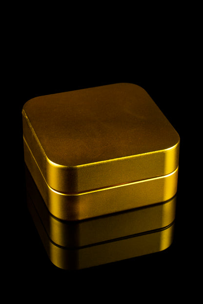 Gold cannabis storage tin with reflective surface, isolated on black.