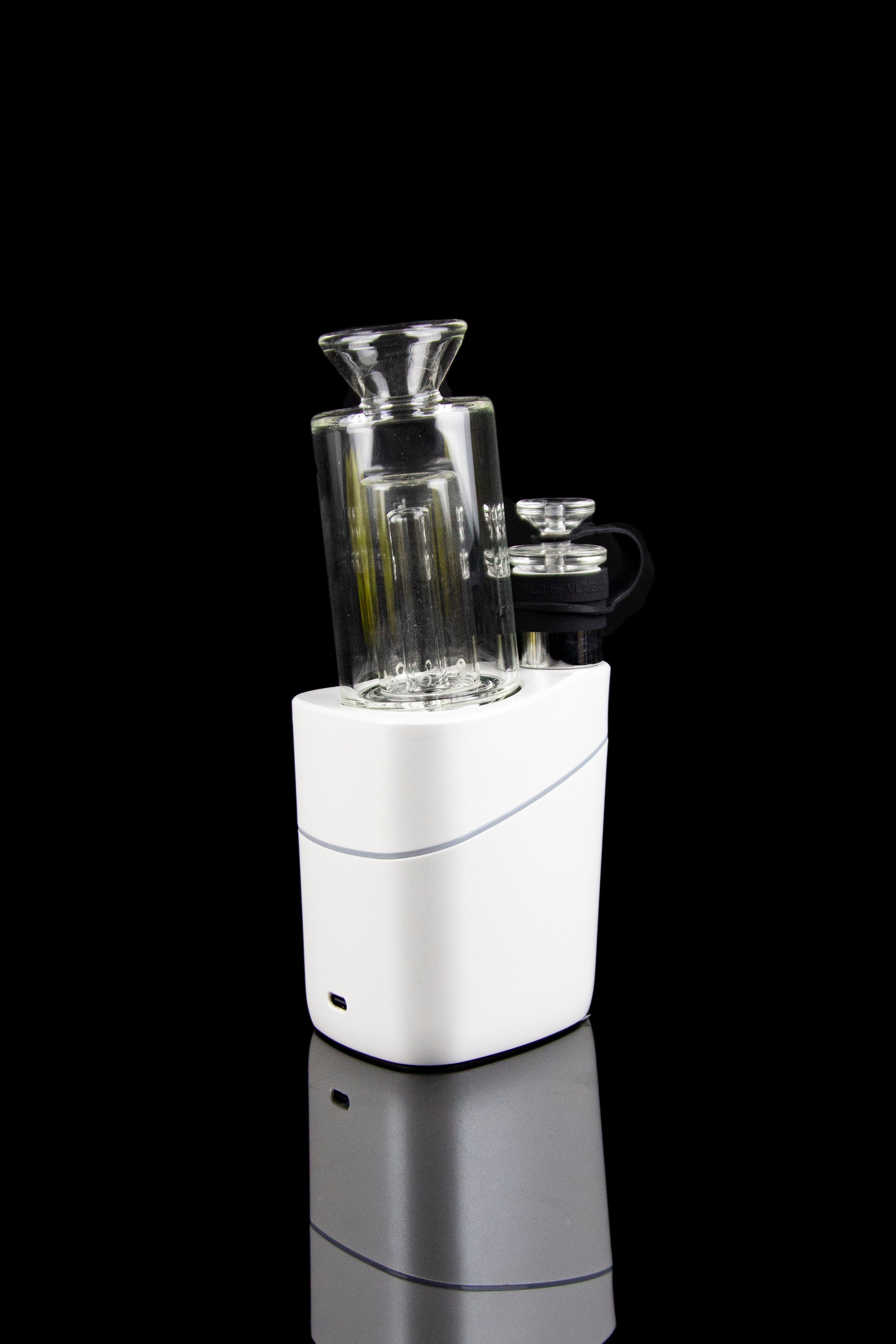 White electronic dab rig with glass water pipe attachment, studio shot on black reflective surface.