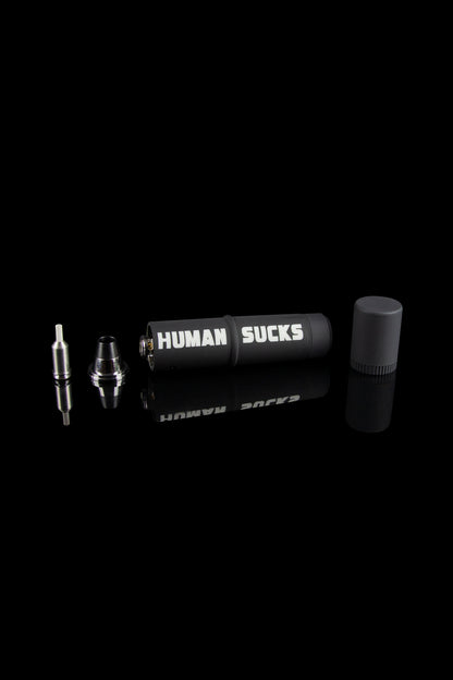 Cannabis oil vape pen components displayed on a black background with "HUMAN SUCKS" printed on the battery.