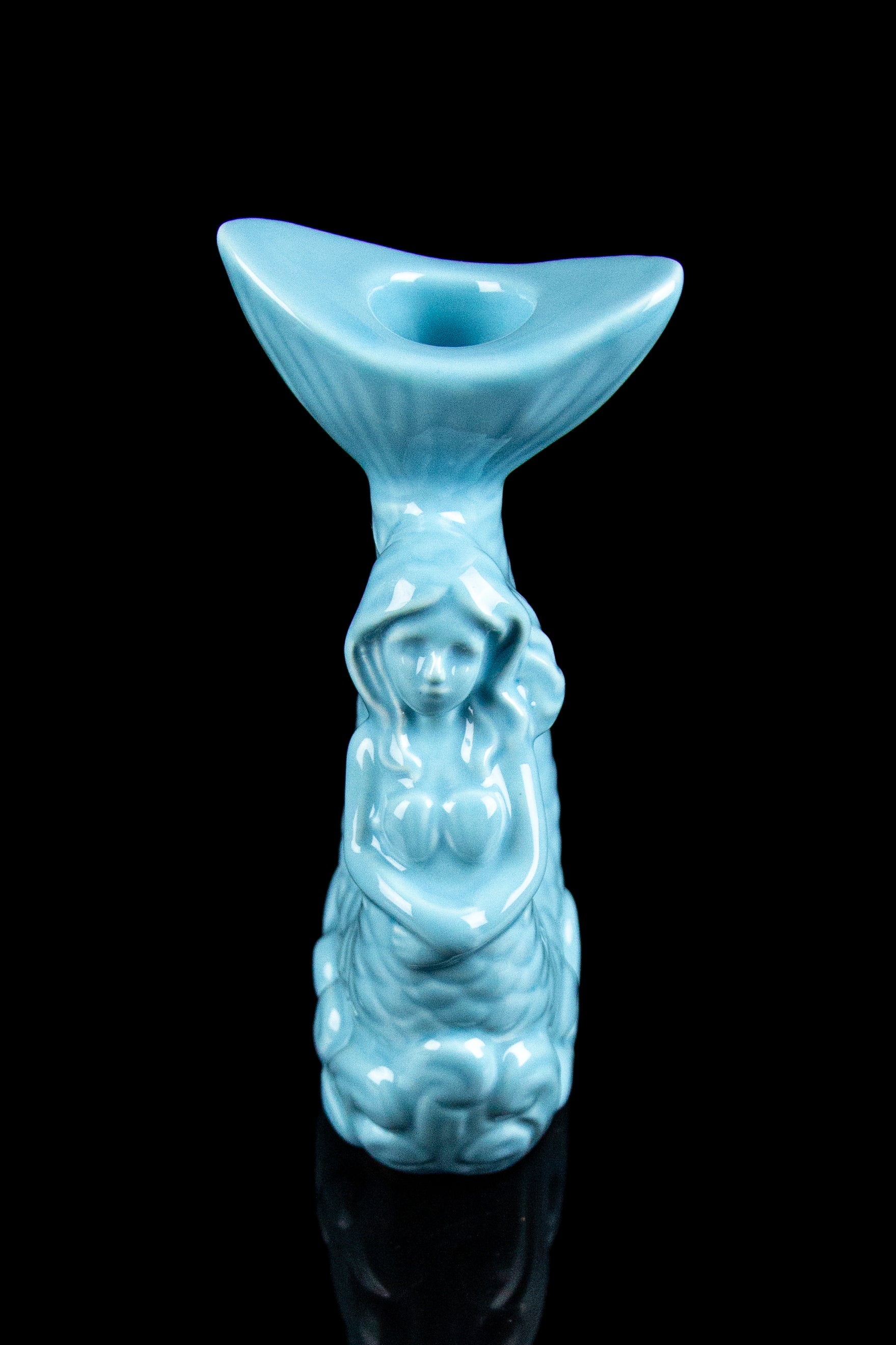 Blue ceramic water pipe shaped like a hooded figure with floral details, reflecting on a black surface.