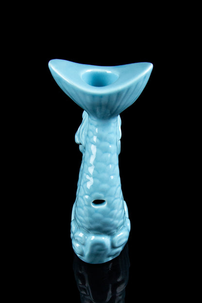 Ceramic cannabis water pipe shaped like a tiki statue, turquoise glaze, black background.
