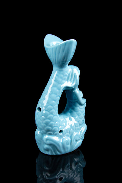Ceramic blue fish-shaped bubbler with carved details, reflecting on a glossy surface.