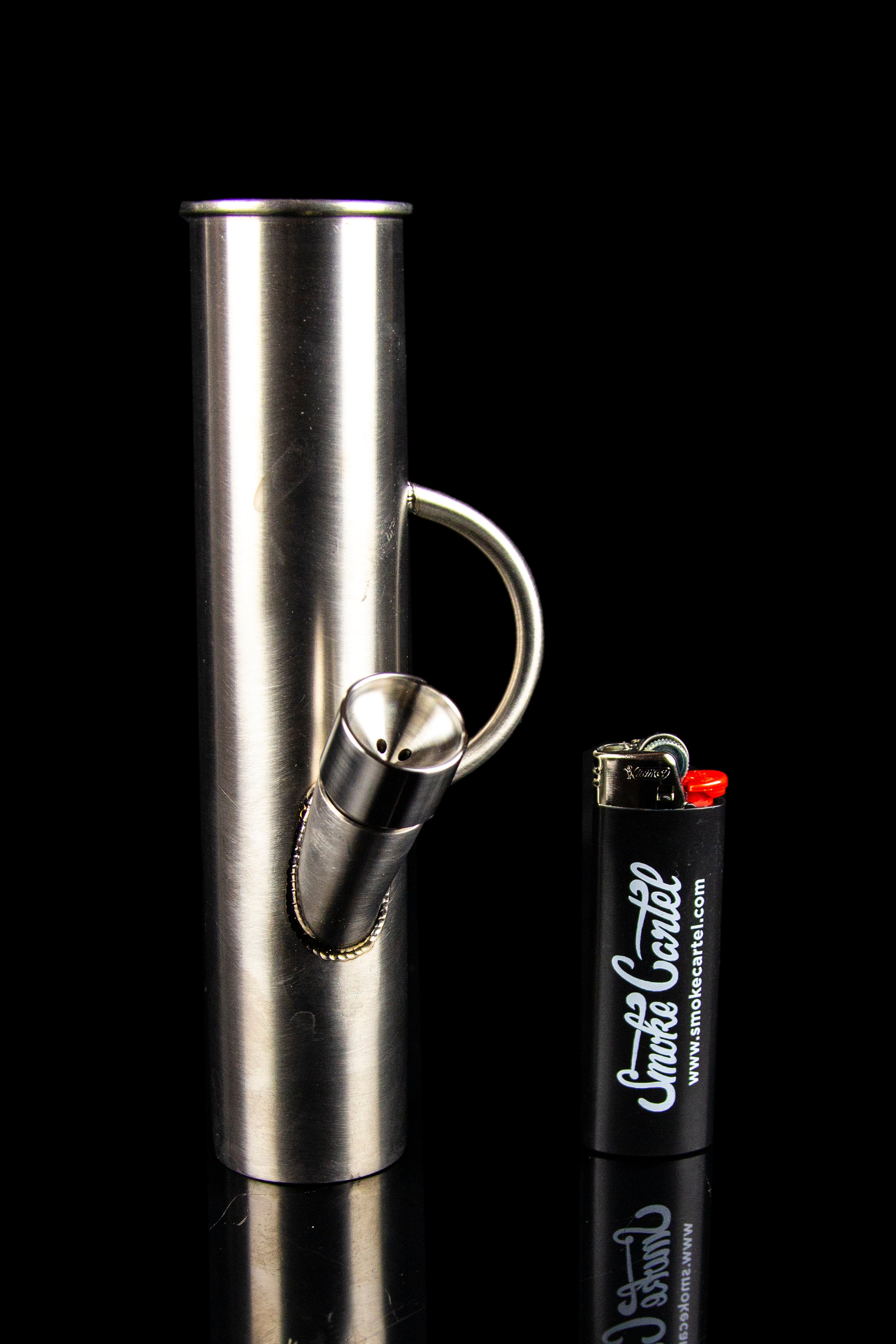 Silver glass pipe and black lighter with "Smoke Cartel" branding against a black background. 