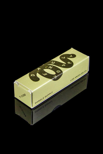 Minimalist packaging for cannabis accessories, featuring a tan box with black “Dangle Supply” logo and “Los Angeles, CA” text, reflected on a glossy black surface.