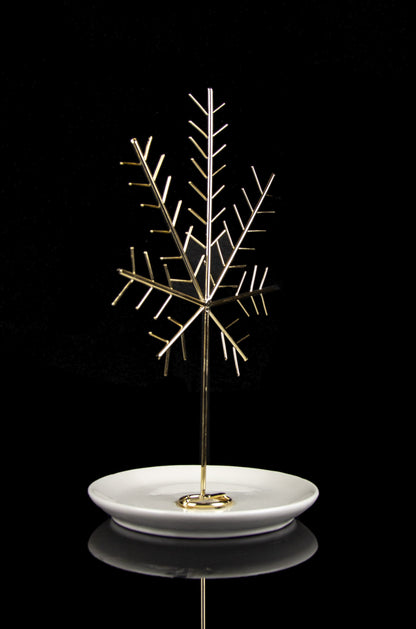 Gold cannabis oil burner with intricate branching design on a white dish, reflecting on a black surface.