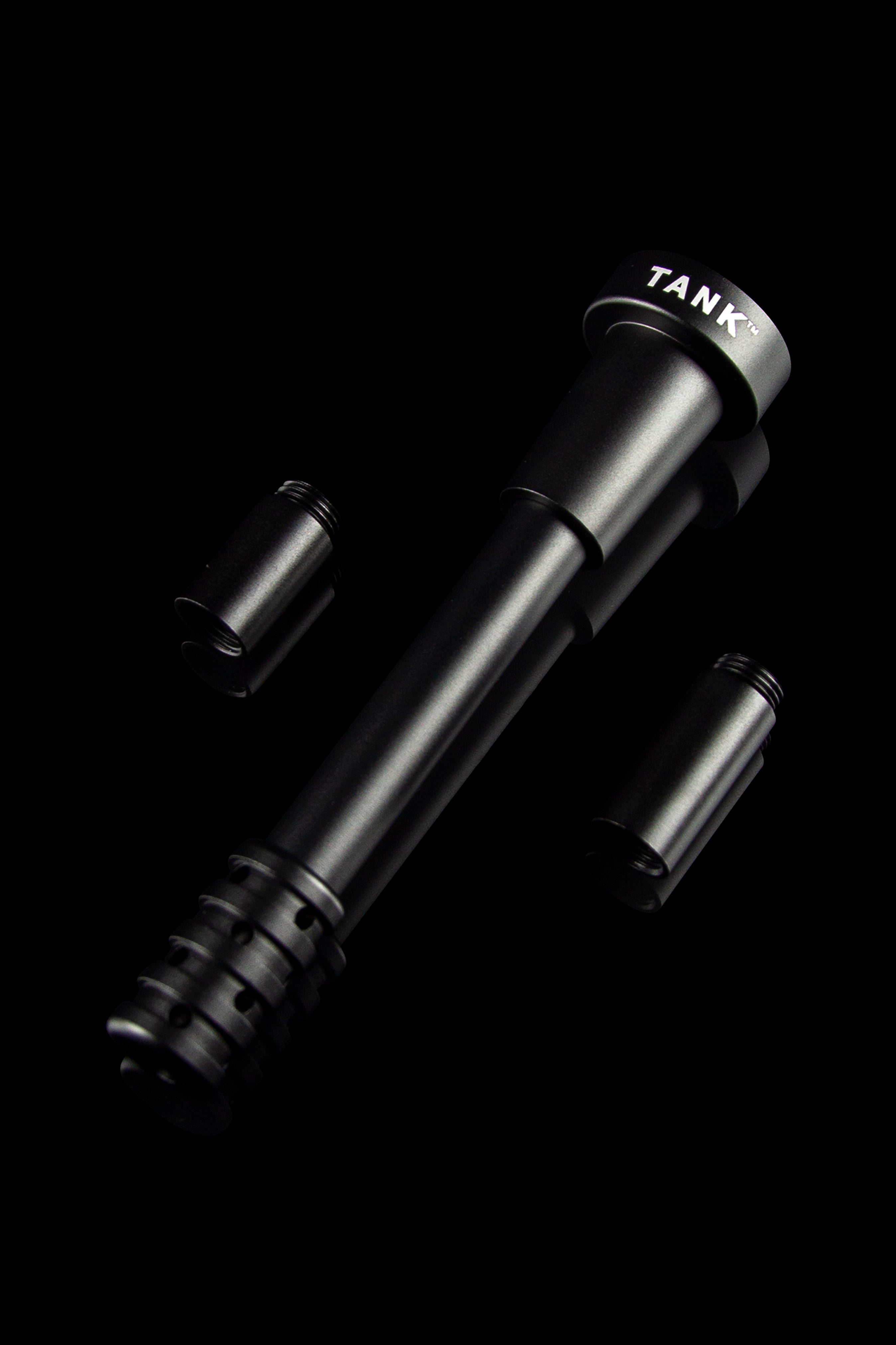 Sleek black cannabis oil burner with two attachments, labeled “TANK™” on the side, against a dark background.