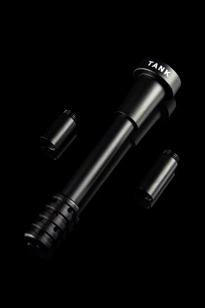 Sleek black cannabis oil burner with two attachments, labeled “TANK™” on the side, against a dark background.