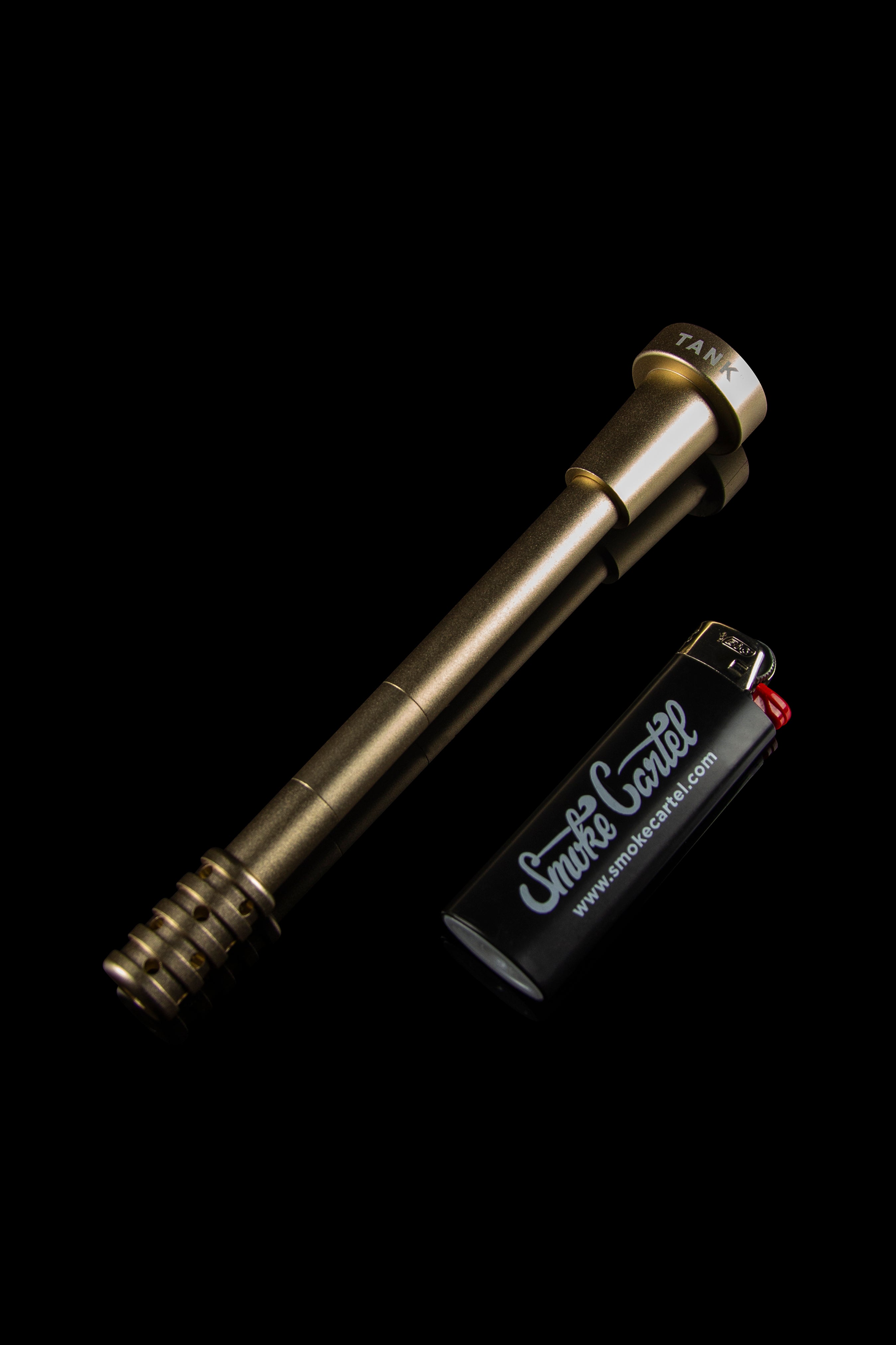 Gold cannabis oil vaporizer pen with a branded lighter on a black background.