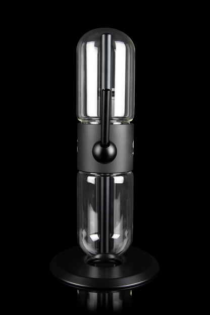 Sleek, black cannabis oil vaporizer (dab rig) with a glass chamber and illuminated heating element, displayed on a circular base.