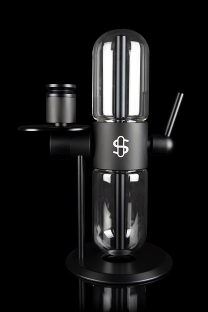 Black glass cannabis rig with a cylindrical percolator chamber and a branded emblem.