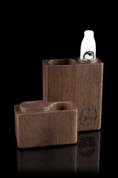 Wooden cannabis smoking box with a skull design and a separate storage compartment, reflecting on a glossy black surface.