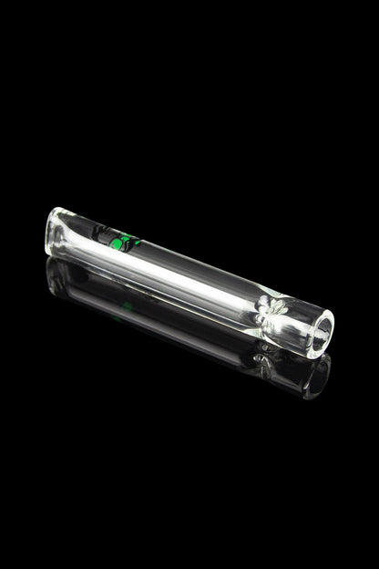 Clear glass smoking pipe with a leaf design, reflecting on a black surface.