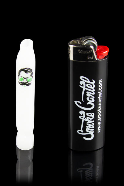 White glass pipe with a cartoon face design next to a black lighter branded with “Smoke Cartel” and website address.