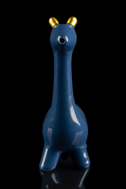 Blue glass water pipe shaped like a giraffe with gold horns, reflected on a black surface.