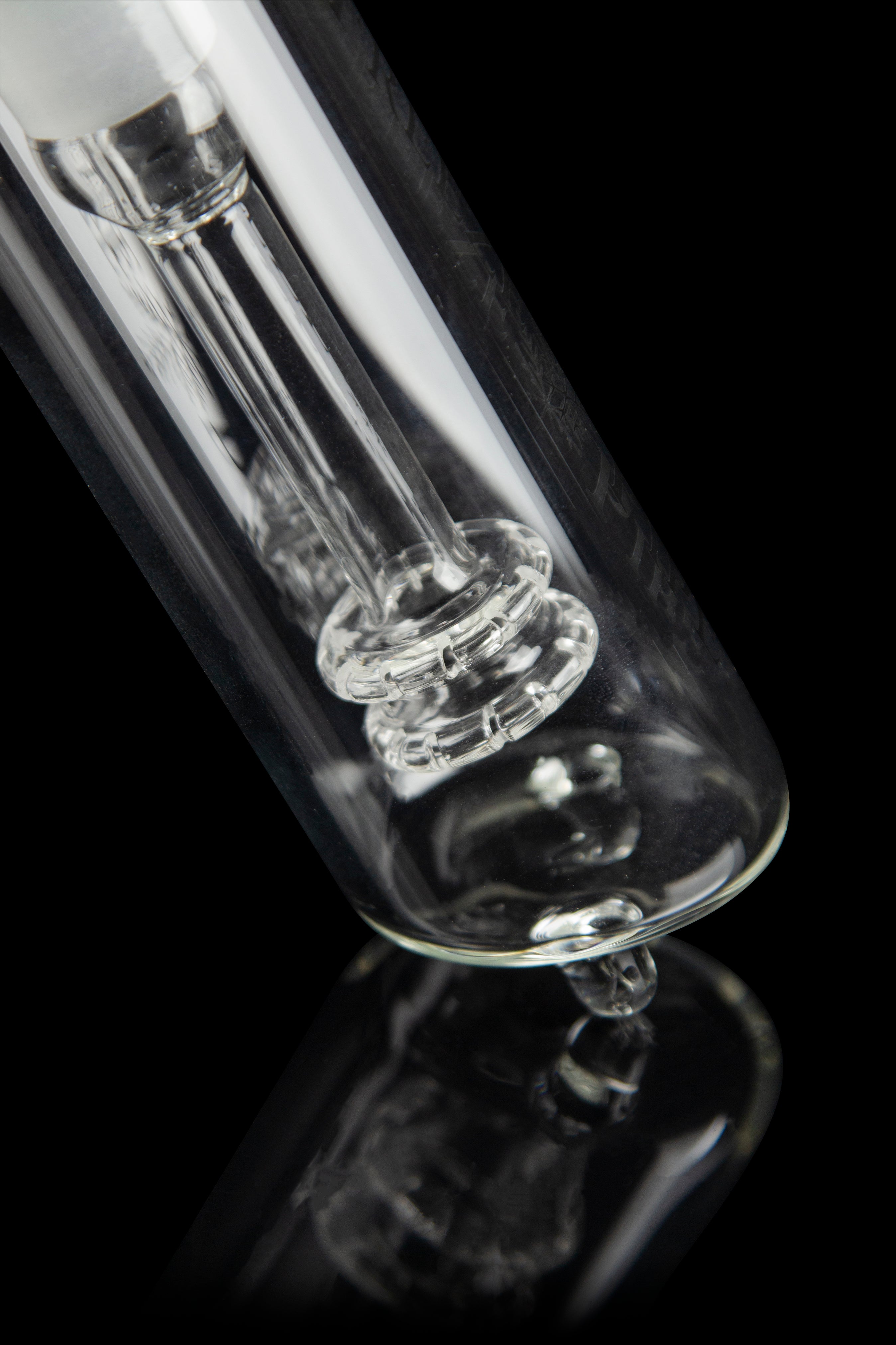 Close-up of a clear glass bong with intricate percolators against a black background.