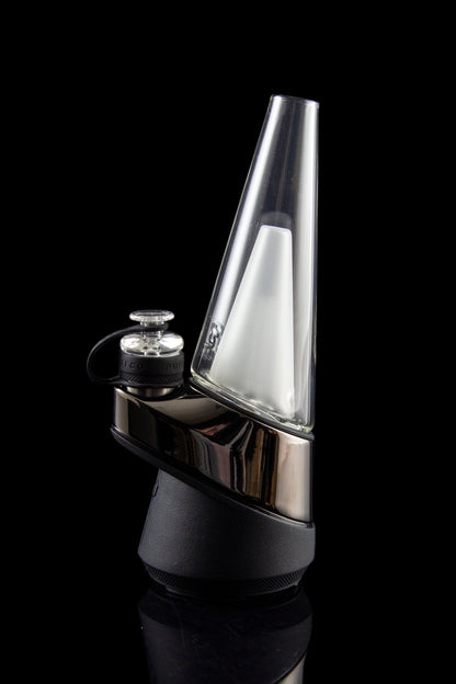 Sleek, silver cannabis dab rig with a conical glass chamber and black base, reflecting light on a dark background.