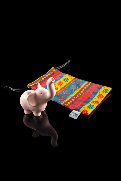 Colorful patterned pouch with a ceramic elephant figure on a reflective surface, suggesting cannabis storage.