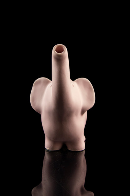 Ceramic elephant-shaped pipe with a raised middle finger, reflected on a dark surface.