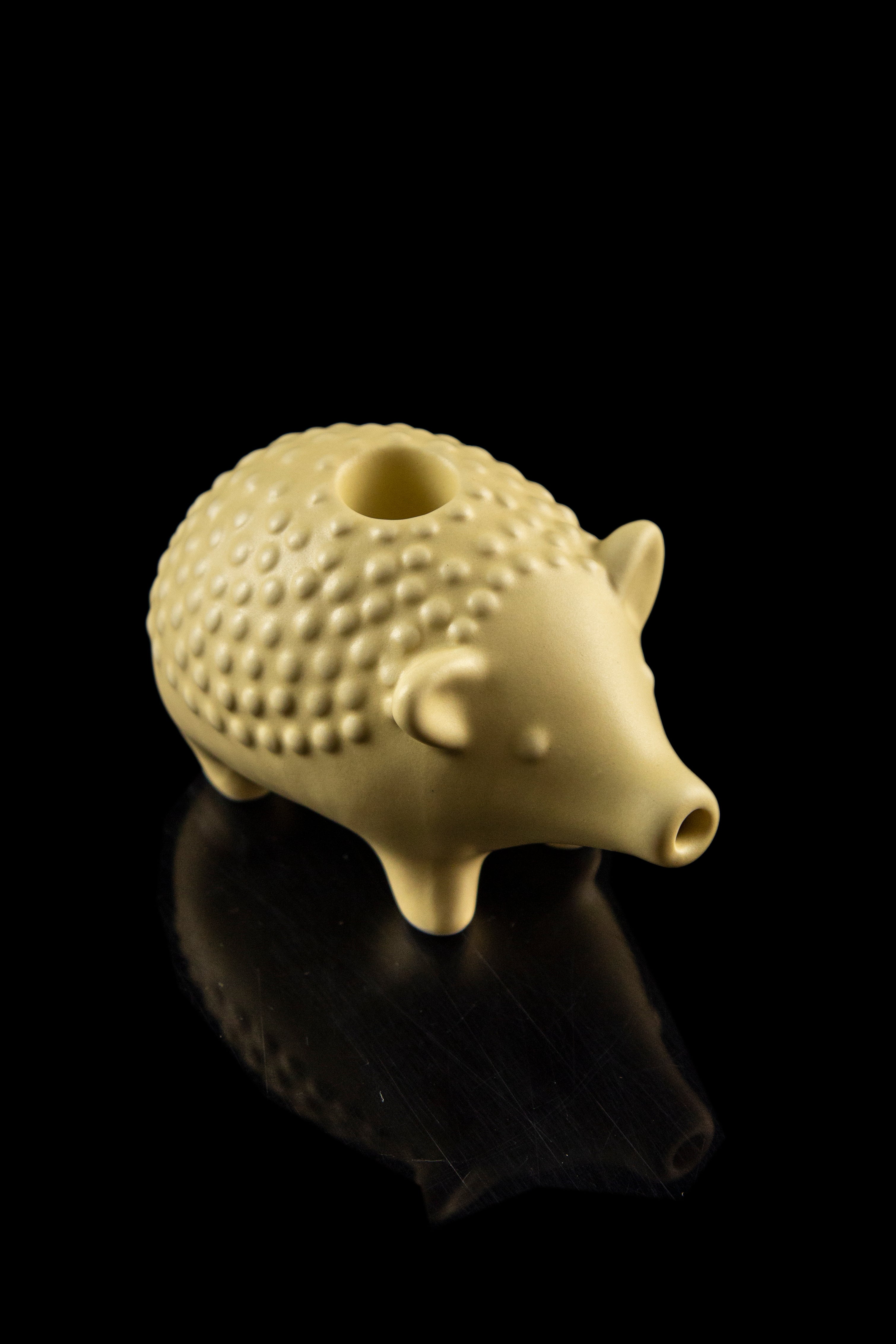 Golden ceramic pipe shaped like a pig with a reflective black surface.