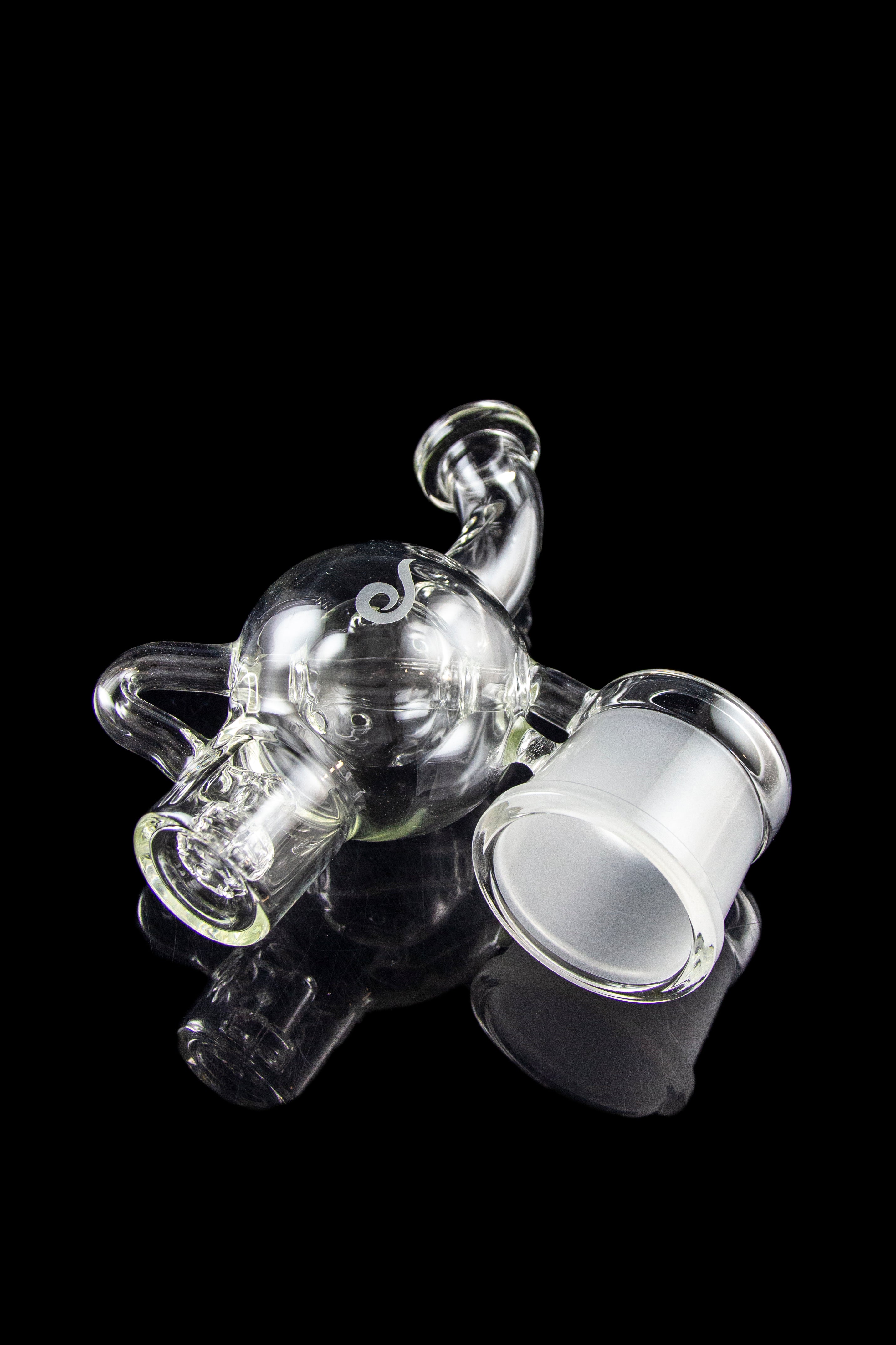 Clear glass rig with intricate bubbler design, isolated on a black background.