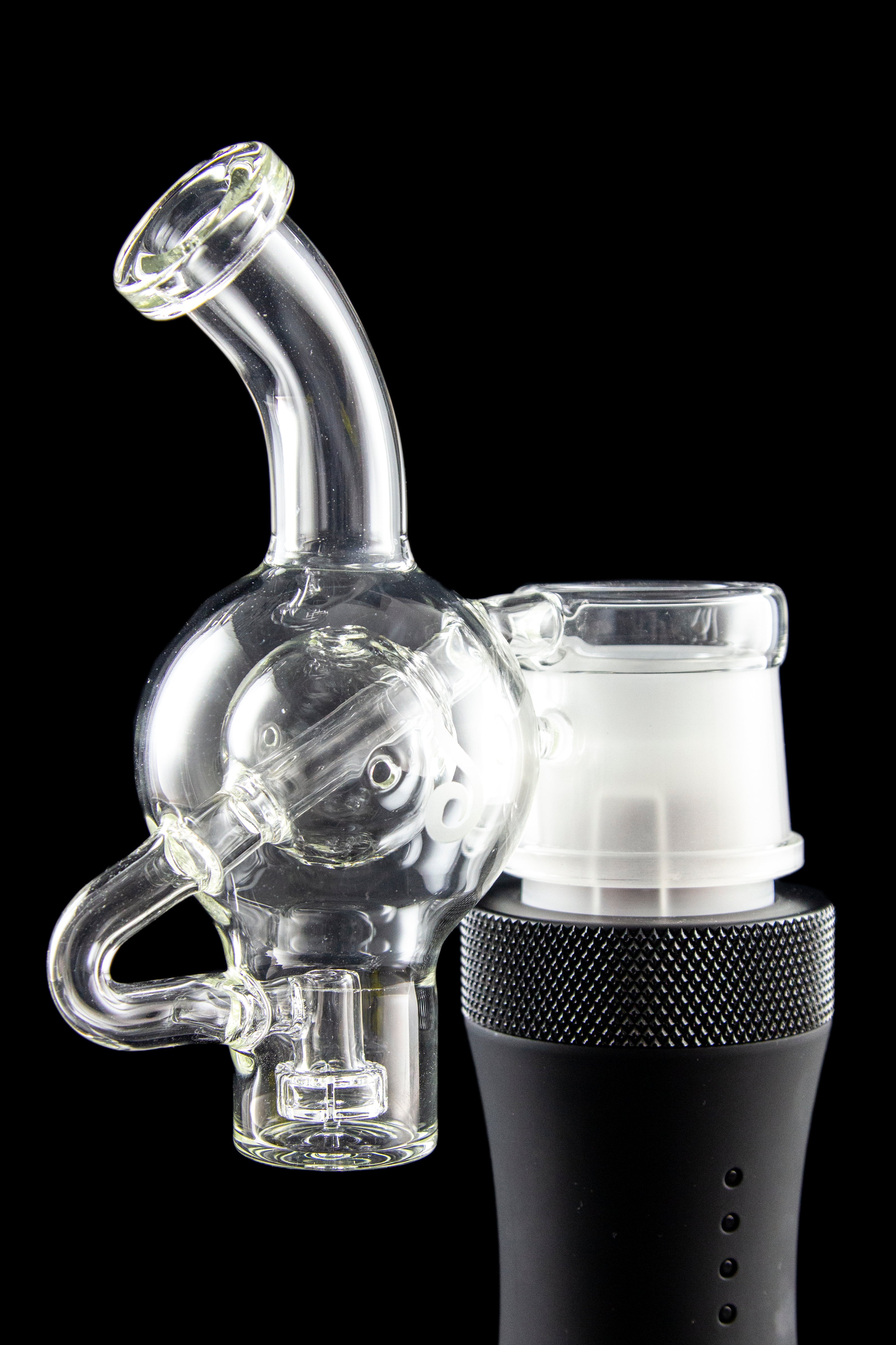 Clear glass water pipe (rig) with a skull-shaped bubbler attached to a black electronic heating device, isolated on a black background.