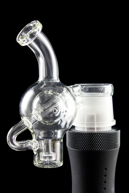 Clear glass water pipe (rig) with a skull-shaped bubbler attached to a black electronic heating device, isolated on a black background.
